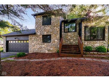 Charming stone-clad home with wooden steps leading to the entrance and an attached two-car garage at 1940 Stringtown Pike, Cicero, IN 46034