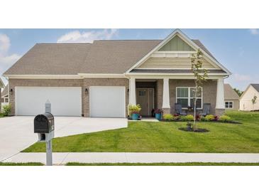 Charming craftsman home featuring a three-car garage and a beautifully landscaped front yard at 3622 S Setting Sun Ln, New Palestine, IN 46163