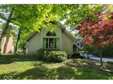 Charming exterior of a light brick home featuring mature landscaping and an arched window detail at 3917 Knoll Wood Ln, Anderson, IN 46011