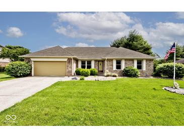 Charming brick home with a well-manicured lawn, an attached garage, and an American flag at 551 Windward Ln, Plainfield, IN 46168