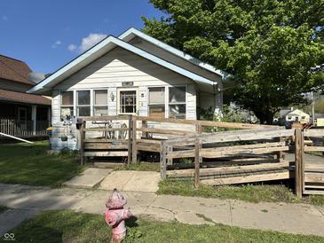 Charming home with a ramped porch, surrounded by mature trees and a well-maintained front yard at 1830 Jefferson St, Anderson, IN 46016