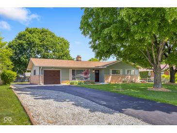 Charming single-story home boasts an attached garage and is enhanced by a lush front yard with mature trees at 8120 E 11Th St, Indianapolis, IN 46219