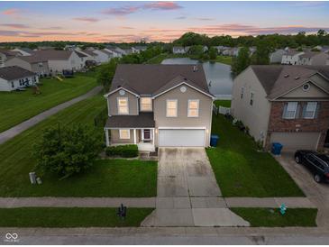 Inviting two-story home with attached two-car garage, water view, and manicured lawn at 8238 Crackling Ln, Indianapolis, IN 46259