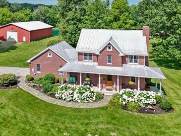 Beautiful two-story brick home featuring a metal roof, covered porch, and meticulously landscaped front yard at 19702 Centennial Rd, Sheridan, IN 46069
