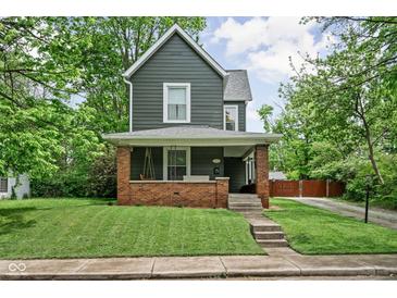 Charming two-story home featuring a welcoming front porch with a porch swing, landscaped yard, and classic architectural details at 31 N Bolton Ave, Indianapolis, IN 46219