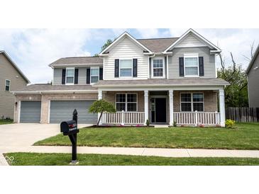 Charming two-story home featuring a welcoming front porch, well-manicured lawn, and a two-car garage at 5824 W Commonview Dr, McCordsville, IN 46055