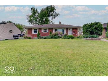Charming brick home featuring a lush front lawn and manicured landscaping at 6069 E 15Th St, Indianapolis, IN 46219