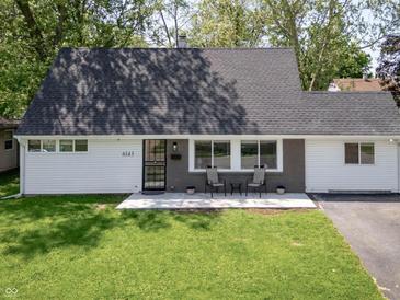 Charming Cape Cod-style home with a manicured lawn and a cozy front porch seating area at 6143 E 43Rd St, Indianapolis, IN 46226