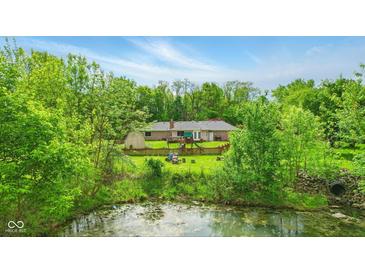 Spacious backyard with mature trees and pond, featuring a play set and a fenced-in area at 6462 Wings Ct, Brownsburg, IN 46112