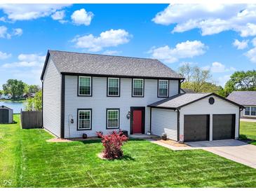 Charming two-story home features a red front door, attached two-car garage and well-manicured lawn at 7670 Lippincott Way, Indianapolis, IN 46268