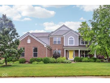 Beautiful two-story home featuring a welcoming yellow front door and lush landscaping at 9311 Windrift Way, Zionsville, IN 46077