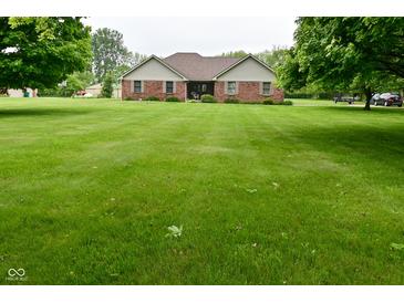 Charming brick home featuring a spacious front yard with mature trees on a partially cloudy day at 2090 W County Road 400 S, Clayton, IN 46118