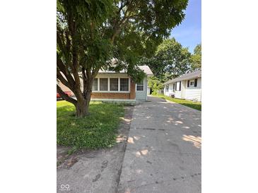 View of a single story home featuring a brick facade, green siding, and a long driveway at 3646 Creston Dr, Indianapolis, IN 46222