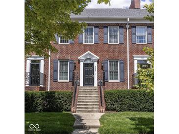 Charming brick townhome with classic blue shutters and meticulously maintained landscaping at 4024 Heyward Pl, Indianapolis, IN 46250