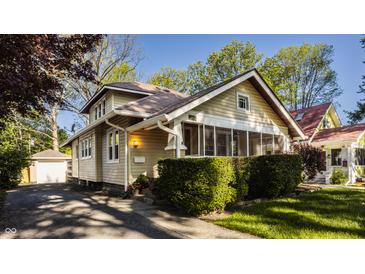 Charming exterior with a screened-in porch, mature landscaping, and a detached garage behind the house at 5622 Guilford Ave, Indianapolis, IN 46220