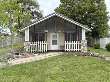 Charming home featuring a cozy front porch with stone accents and a white picket fence at 909 Sullivan St, Alexandria, IN 46001