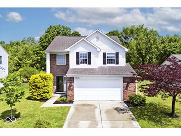 Charming two-story home with brick and white siding, lush green lawn, and a two car garage at 10876 Trailwood Dr, Fishers, IN 46038