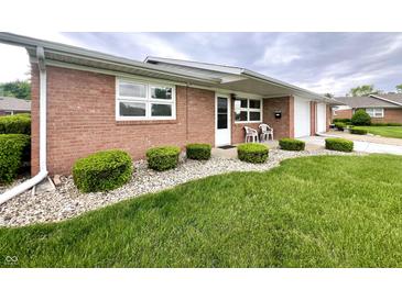 Charming brick home with well-maintained lawn and landscaping with outdoor chairs on the front porch at 2508 Pamela Ct, Anderson, IN 46012