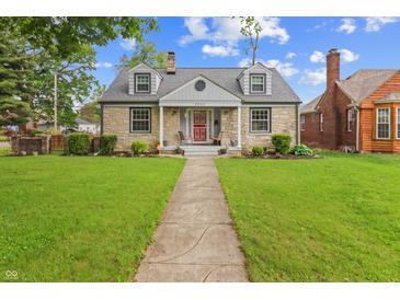 Charming stone house with a well-manicured lawn and inviting front porch and a traditional walkway to the front door at 3702 N Chester Ave, Indianapolis, IN 46218