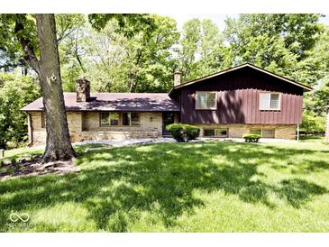 A charming exterior of a home with stone and wood siding, surrounded by lush greenery and mature trees at 6248 Graham Rd, Indianapolis, IN 46220