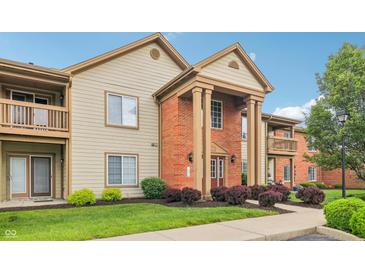 Inviting condominium exterior with manicured lawn, beautiful shrubs, and brick entryway at 8910 Hunters Creek Dr # 207, Indianapolis, IN 46227