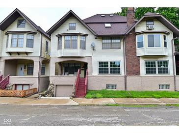 Charming three-story home featuring a red staircase leading to a covered front porch with a garage underneath at 122 E 27Th St, Indianapolis, IN 46205