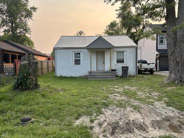 Exterior of a charming one-story home with a metal roof in need of lawn care and repairs at 4106 N Pasadena Ave, Indianapolis, IN 46226