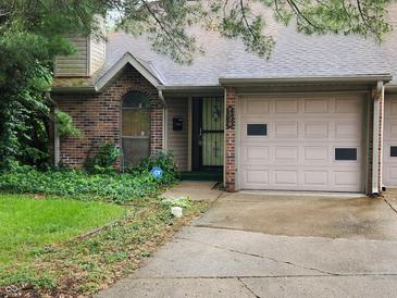 Traditional brick townhome featuring a garage, complemented by a well-maintained yard at 4336 Abby Creek Ln, Indianapolis, IN 46205