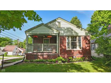 Charming brick home featuring a cozy front porch with hanging floral baskets and well-maintained landscaping at 6102 Primrose Ave, Indianapolis, IN 46220