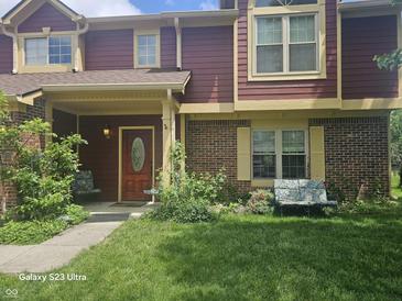 Charming townhouse featuring a covered porch, brick accents, and well-manicured front yard at 6723 Silver Tree Dr, Indianapolis, IN 46236