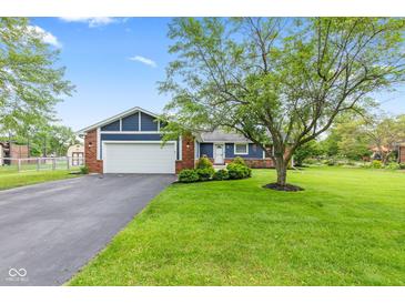 Charming home with a blue facade, brick accents, well-manicured lawn, and a mature shade tree enhancing curb appeal at 2309 Alexandria Dr, Greenfield, IN 46140
