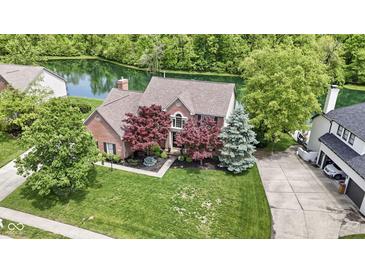 Beautiful brick home with mature trees and a well-manicured lawn overlooking a serene pond at 3708 Gould Dr, Carmel, IN 46033
