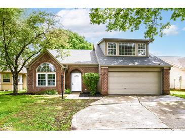 Charming brick home featuring a two-car garage, arched window, and inviting front entrance, complete with lush landscaping at 6471 Hunters Green Pl, Indianapolis, IN 46278