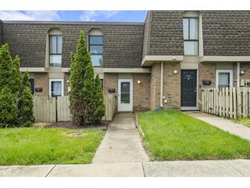 Charming townhome featuring brick facade, well-manicured lawn, and inviting entryway with tree at 7334 Country Brook Dr, Indianapolis, IN 46260