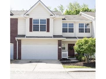 Charming two-story townhome featuring a spacious garage and a welcoming front entrance with beautiful landscaping at 8317 Pine Branch Ln, Indianapolis, IN 46234