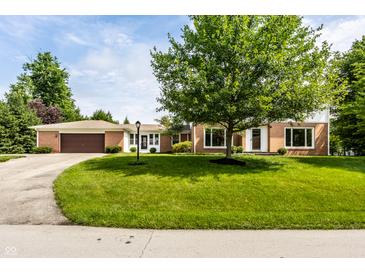 Beautiful brick home featuring an attached garage, a well-manicured lawn and a large tree in the front yard at 100 Wellington Rd, Indianapolis, IN 46260