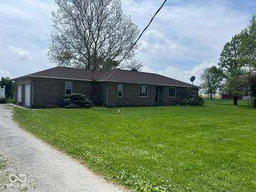 Spacious single-story brick home featuring a large lawn, mature trees, and attached two-car garage at 1925 W State Road 32, Lebanon, IN 46052