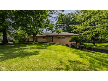 Well-maintained one-story home with brick facade, mature trees, and green lawn at 7887 Meadowbrook Dr, Indianapolis, IN 46240