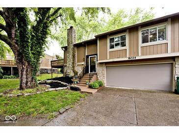 Charming home featuring stone accents, landscaping, and an attached two-car garage at 8024 Sunfield Ct # 5-B, Indianapolis, IN 46214