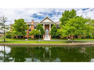 Stunning exterior view of a brick condo building with water feature and lush green landscaping at 8690 Jaffa Ct W Dr # 28, Indianapolis, IN 46260