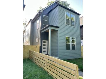 Two-story home with green siding, a modern front door, and a well-maintained lawn and wooden fence at 39 N Walcott St, Indianapolis, IN 46201