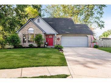 Charming brick home features a bright red front door and well-manicured lawn, and an attached two-car garage at 410 Wood Hollow Ct, Westfield, IN 46074