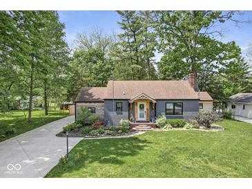 Charming home featuring a well-manicured lawn, beautiful landscaping, and a cozy front porch at 6110 Orinoco Ave, Indianapolis, IN 46227