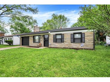 Charming single-story home featuring a stone facade, attached garage, and a well-maintained lawn at 7625 E 35Th St, Indianapolis, IN 46226