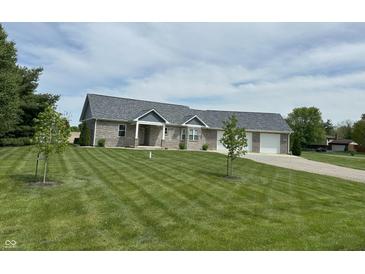 Charming brick home featuring an attached two-car garage and a well-manicured lawn at 951 N Maiellen Dr, Greenfield, IN 46140