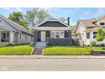 Charming home with a well-manicured lawn, gray siding, inviting front porch, and steps at 1016 Churchman Ave, Indianapolis, IN 46203