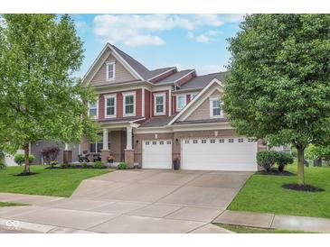 Inviting two-story home features a three-car garage, red siding and a well-manicured lawn at 14075 Knightstown E Dr, Carmel, IN 46033