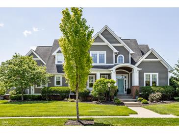 Charming gray two-story home with manicured lawn, blue door and mature tree at 1799 Hourglass Dr, Carmel, IN 46032