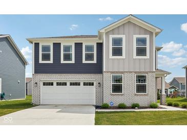 Beautiful two-story home featuring a two-car garage, brick accents, and eye-catching blue and gray siding at 1807 Orchard Dr, Fortville, IN 46040