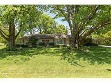 Charming single-story home with stone exterior and mature trees in a well-maintained front yard at 7401 Spring Mill Rd, Indianapolis, IN 46260